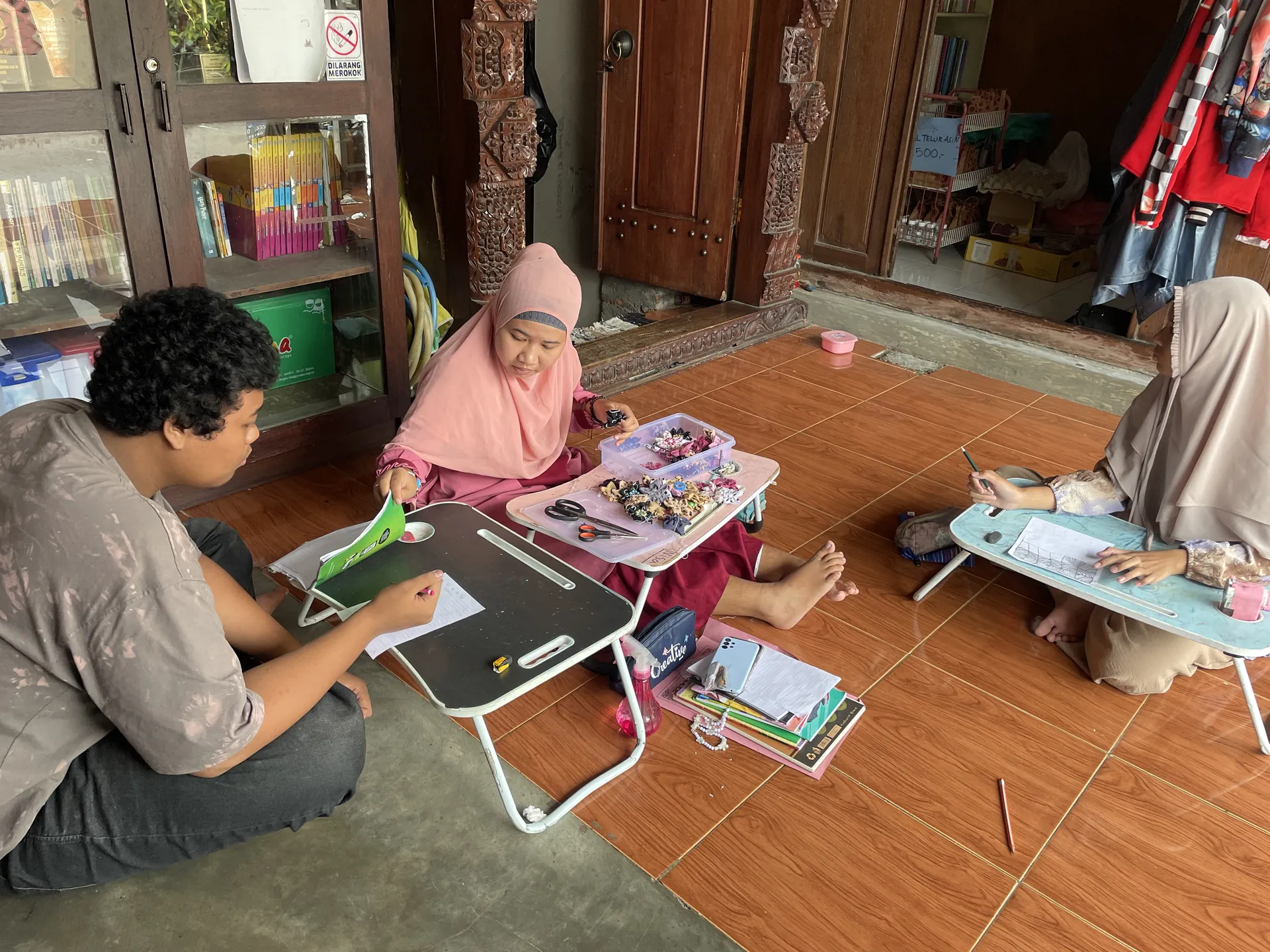 Siswa belajar dengan meja lipat di lantai rumah didampingi guru, suasana belajar YUKA di Sleman