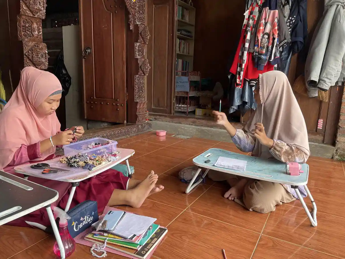Dua perempuan berhijab belajar bersama, menggambarkan pendampingan dan dukungan dalam proses belajar anak berkebutuhan khusus