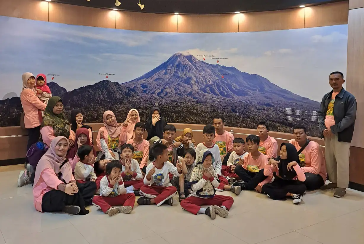 Anak-anak dan pendamping berfoto bersama di ruang museum dengan gambar gunung di belakangnya