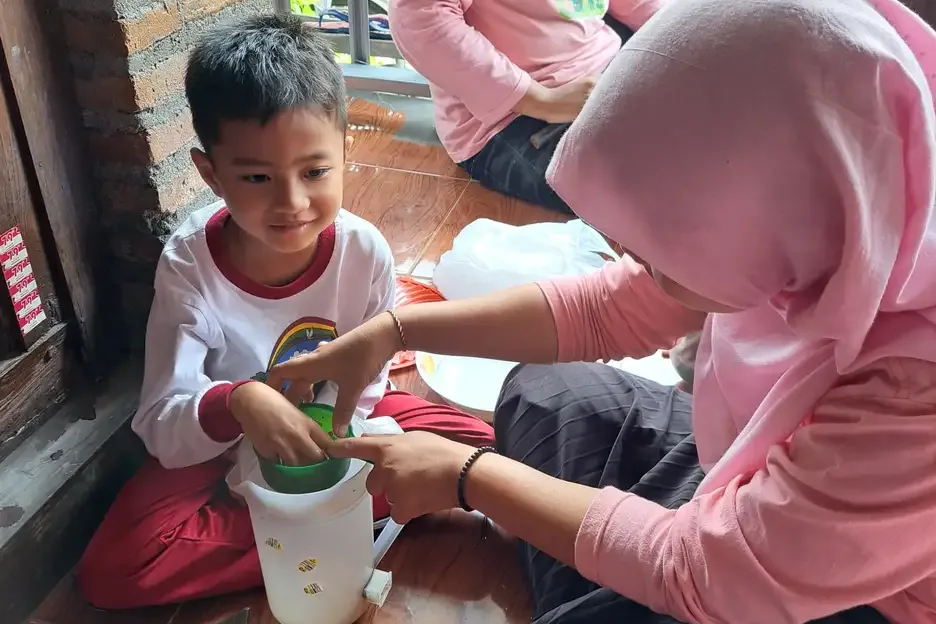Pendamping membimbing anak mencampur bahan dalam wadah pada kegiatan belajar di rumah