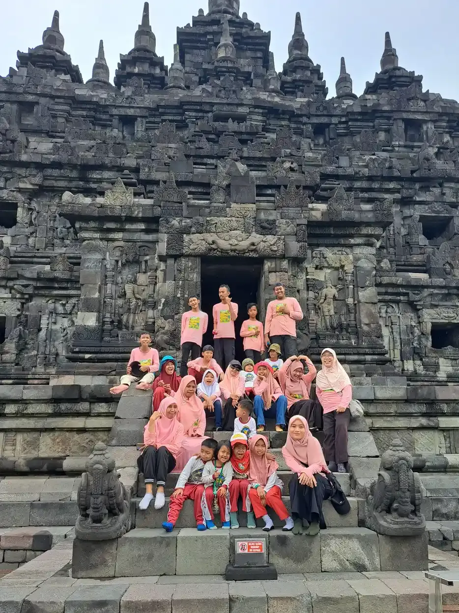 Rombongan anak dan pendamping berfoto bersama di anak tangga candi batu yang tinggi