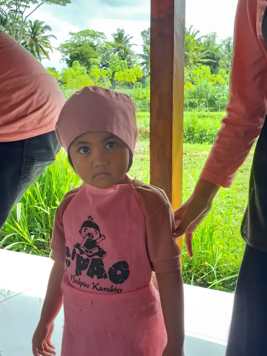 Anak kecil berdiri di teras rumah sebagai ilustrasi perkembangan motorik dan kemandirian anak dengan kebutuhan khusus