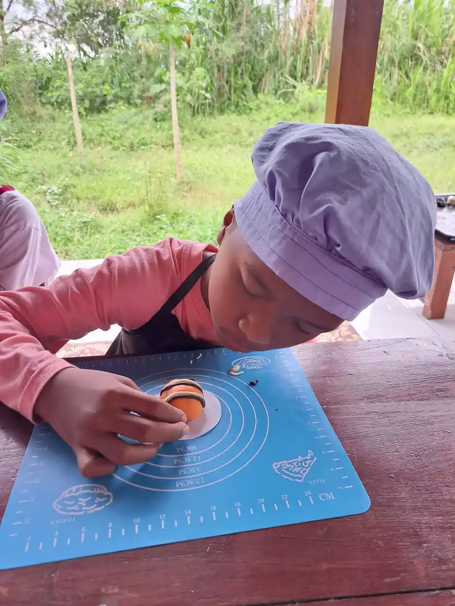 Anak-anak di YUKA sedang membuat adonan kue bersama sebagai kegiatan stimulasi motorik halus