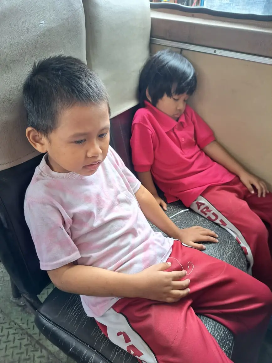 Dua anak duduk santai di sofa saat waktu istirahat di rumah